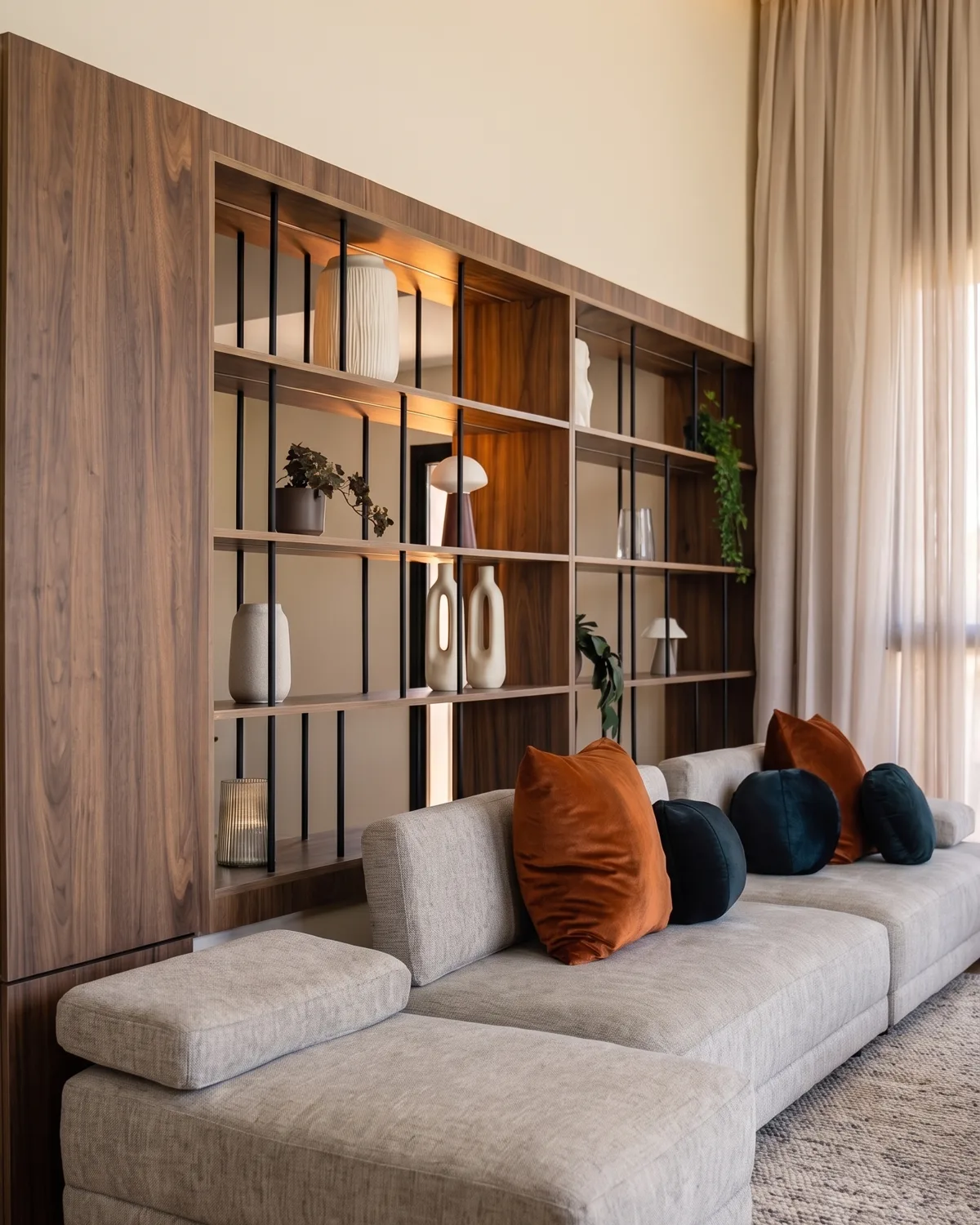 Le séjour de la villa témoin Jnane Oum El Ghite — canapé réuni devant la bibliothèque en noyer, coussins terracotta, photographié sur place