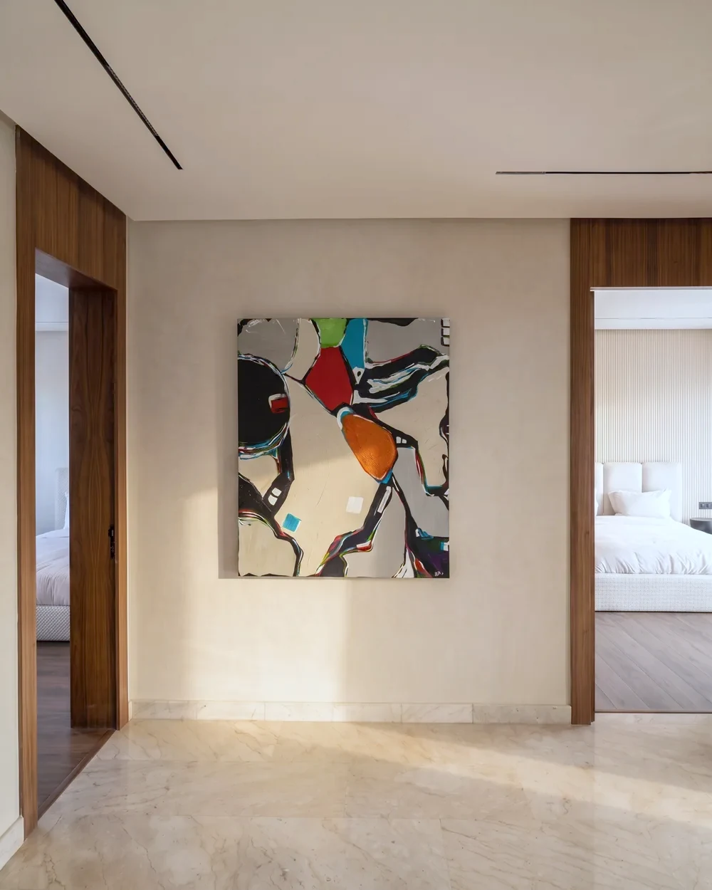 La galerie de la villa témoin — œuvre colorée au mur et enfilade en noyer vers la chambre baignée de lumière, photographiée sur place