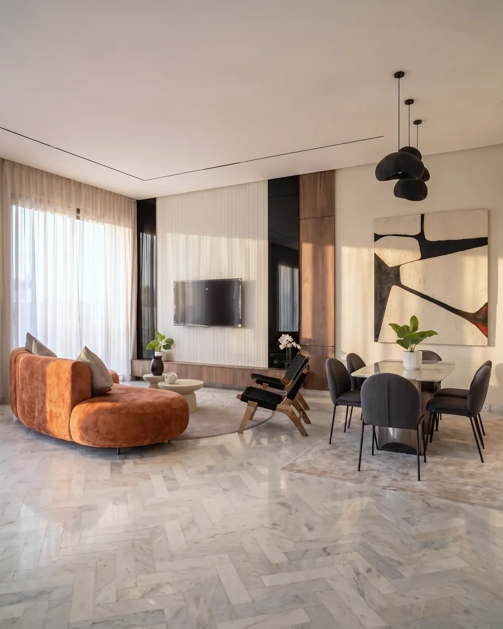 Le séjour ouvert de la villa témoin — salon, salle à manger et mur média en noyer d’un seul tenant, photographié sur place