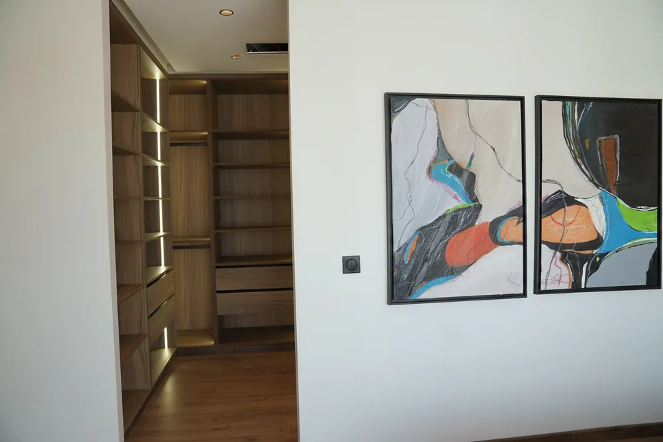 Le dressing de la villa témoin, depuis la chambre — noyer et éclairage intégré aux étagères, photographié sur place.